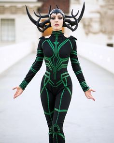 a woman dressed in black and green with horns on her head