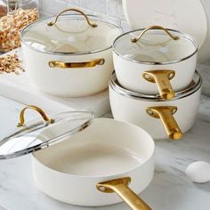 white pots and pans with gold handles on a counter