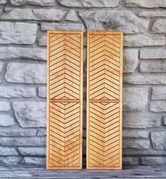 two wooden doors sitting next to each other on top of a stone wall in front of a brick wall