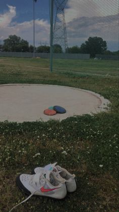 two pairs of shoes sitting on the ground in front of a baseball field and net