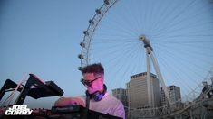 a man with headphones on playing music in front of a ferris wheel