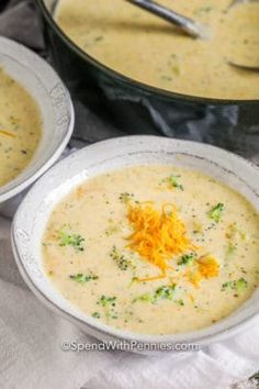 two bowls of broccoli cheese soup on a table