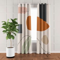 a potted plant sitting next to a window in front of a curtain with an abstract design