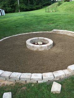 a stone fire pit surrounded by grass and rocks