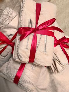 three folded towels with red ribbons tied around them and wrapped in white cloth, on top of each other