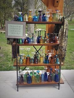 a shelf filled with lots of different colored glassware on top of a cement floor