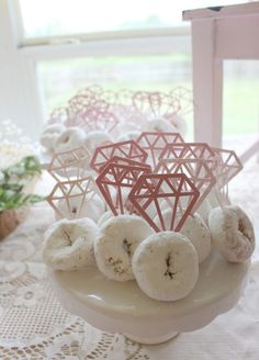 doughnuts are arranged on a plate in front of a window with lace doily