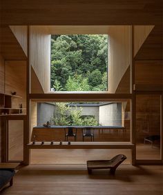 an open room with wooden walls and floor to ceiling windows that look out onto the forest