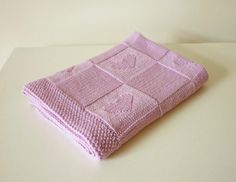 a pink knitted blanket sitting on top of a white table next to a sign that says do it yourself / pattern