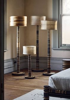 three lamps sitting next to each other on top of a wooden floor near a window