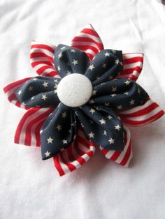 a red, white and blue flower brooch with stars on the side sitting on top of a bed