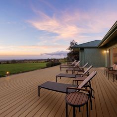 there are many lounge chairs on the deck by the door to the house at sunset