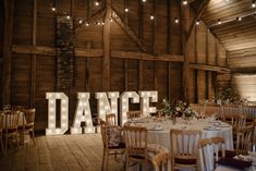 a large dance sign is lit up in the middle of a room with tables and chairs