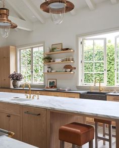 a kitchen with wooden cabinets and white marble counter tops, two pendant lights over the island