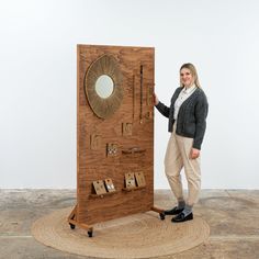 a woman standing next to a wooden display case with mirrors and keys on the wall