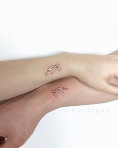 two people with tattoos on their arms holding each other's hands and one has a dolphin tattoo on it