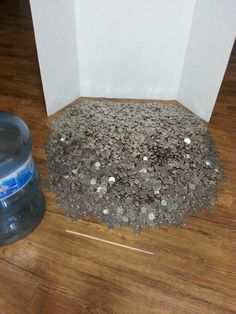 a bottle of water sitting on top of a wooden floor next to a pile of gravel