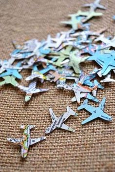 several pieces of paper cut into the shape of airplanes with words on them, sitting on a piece of burlap