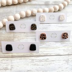 three pairs of leopard print studs on white cards next to a bead necklace