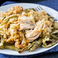 a white plate topped with green beans covered in chicken and breadcrumbs next to a fork