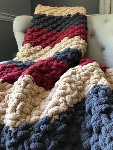 a crocheted blanket sitting on top of a couch next to a white chair