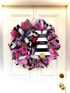 a pink, black and white zebra print deco mesh wreath on a door with gold hardware