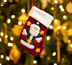 a christmas ornament hanging from a tree with lights in the background and a santa clause stocking on it