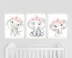 three elephants with flowers on their heads are hanging in a white nursery room next to a crib