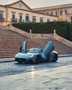 a car with its doors open sitting in front of some stairs and steps that lead up to the building