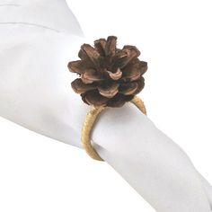 a pine cone on top of a napkin with a gold ring around it's edge