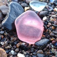 a pink rock sitting on top of a pile of rocks next to gravel and pebbles