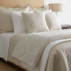 a bed with white sheets and pillows in a bedroom