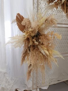 dried flowers and feathers in front of a white curtain