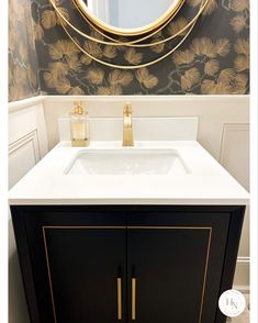 a bathroom vanity with a mirror above it and a gold leaf wallpaper behind it