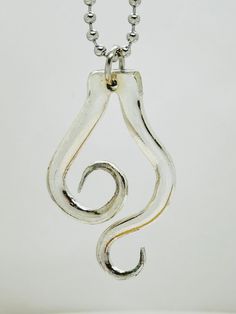 a silver necklace with a spiral design hanging from it's side on a chain