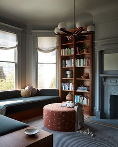 a living room filled with furniture and a fire place in front of a book shelf