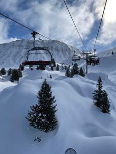 the ski lift is going over the snow covered mountain side, with trees on both sides