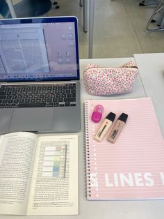 an open laptop computer sitting on top of a desk next to a notebook and pen