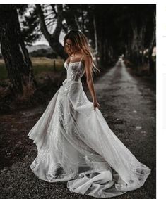 a woman in a white dress is walking down the road