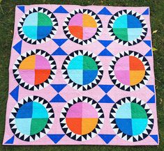 a colorful quilt on the grass with circles and squares in it, all made up of different colors