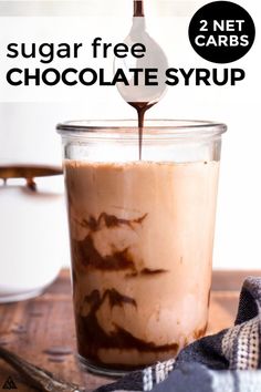 a spoon is pouring chocolate into a glass jar with ice cream in it on a wooden table