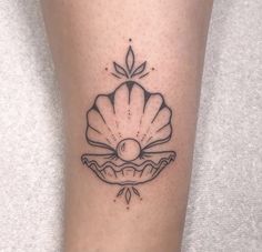 a black and white photo of a shell tattoo on the right leg with a pearl in it