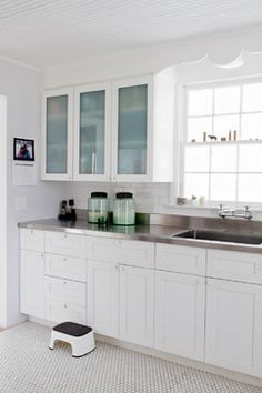 a kitchen with white cabinets and stainless steel counter tops, along with a dog bowl on the floor