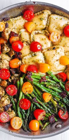 a pan filled with chicken, tomatoes and asparagus