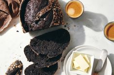 slices of chocolate bread and butter on a white plate next to two cups of coffee