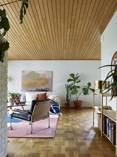 a living room filled with furniture and potted plants on top of a hard wood floor