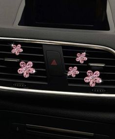 pink flowers are placed on the dashboard of a car with black dash board and air vent