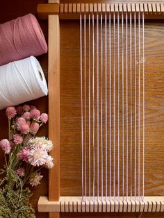 a close up of a weaving machine with yarn and flowers on the table next to it