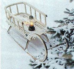 an old fashioned sleigh in the snow with a lit candle on it's side