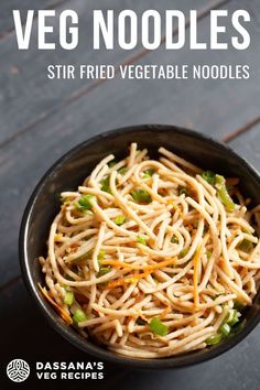 a black bowl filled with noodles and vegetables on top of a wooden table next to chopsticks